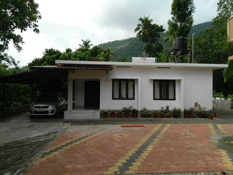 The exterior of Kattakayam Heavens, a private house with hills rising behind it